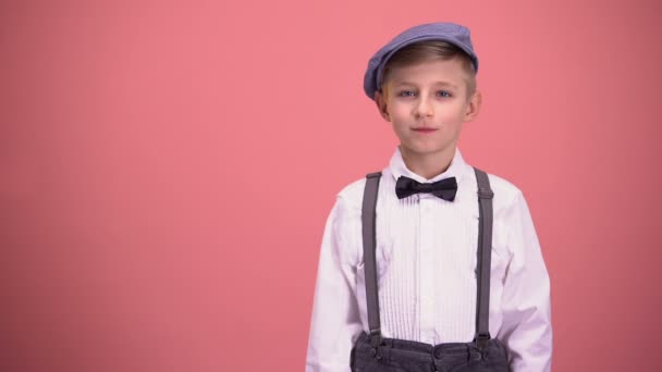 小男孩在复古衣服看着照相机 被隔绝在粉红色背景 — 图库视频影像