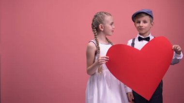 Kırmızı kalp kesme tutarak ve gülümseyen çocuklar çift, Sevgililer günü, aşk kavramı