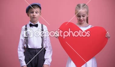 Küçük kızla erkek çocuk recoils, Genç çocuk öpücüğü vermeye kırmızı kağıt kalp ile