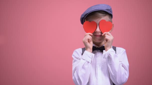 バレンタインの休日に赤いハートの目を閉じてのビンテージの服で学校の男の子 — ストック動画