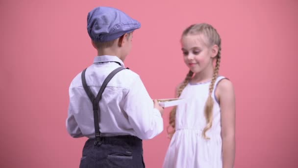 Kleiner Junge überreicht Schokoladenbonbons an überraschte Freundin, Valentinstag — Stockvideo