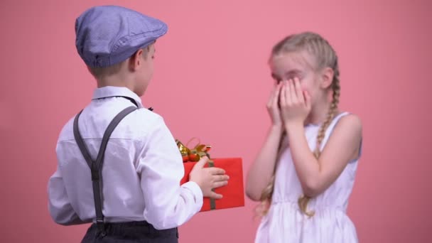 Gallant boy sorprendiendo a su pequeña novia con regalo, celebración de cumpleaños — Vídeos de Stock