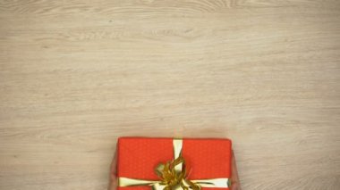 Eller kadın koyarak hediye kutusu ahşap arka plan, tatil kutlaması, üstten görünüm