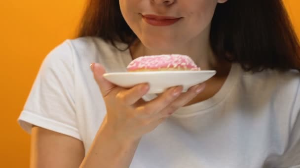 满意漂亮的女孩显示粉红色釉面甜甜圈进入相机 糖尿病的风险 — 图库视频影像