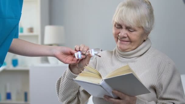 Infermiera Supporto Dando Occhiali Paziente Donna Anziana Anziana Signora Libro — Video Stock