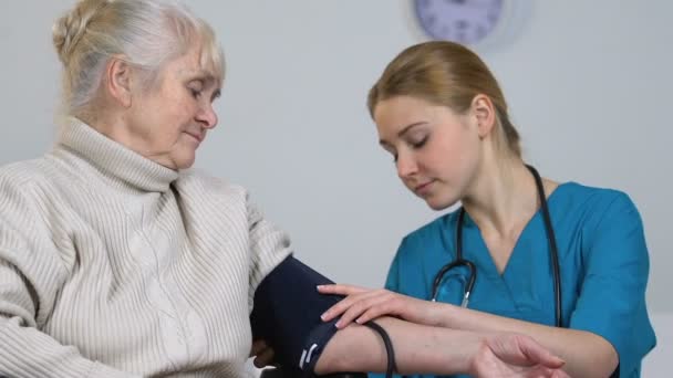 Młoda Pielęgniarka Pomiar Wyłączone Starszych Kobiet Ciśnienie Krwi Biorąc Rekordy — Wideo stockowe