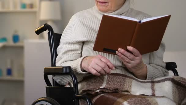 車椅子の高齢者のおばあちゃん読書に眼鏡を与える若い女性を気遣うこと — ストック動画