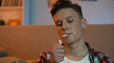 Genç çocuk oturma ev ve sigara sigara, zararlı sağlıksız alışkanlık, kanser