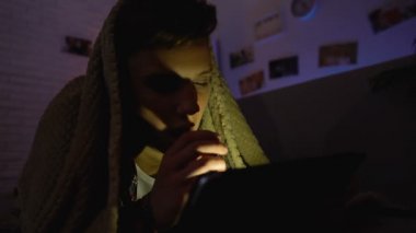 Uyku, yerine sekmesinde Internet sörf yorgun genç battaniyenin altında yalan