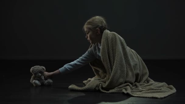 暗い部屋 孤児院の施設でスリープ状態に格子縞のテディベアをカバーし 横になっている少女 — ストック動画