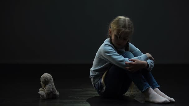 沮丧的小女孩感到孤独 抱着泰迪熊 坐在黑暗的房间里 — 图库视频影像