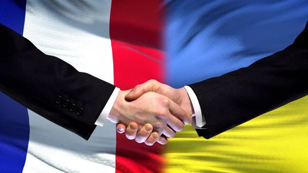 France and Ukraine handshake, international friendship relations flag background