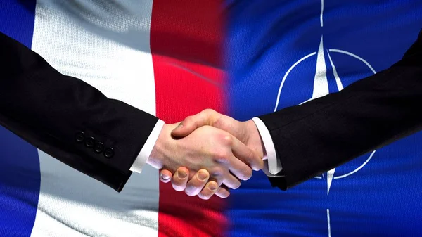 France and NATO handshake, international friendship relations, flag background
