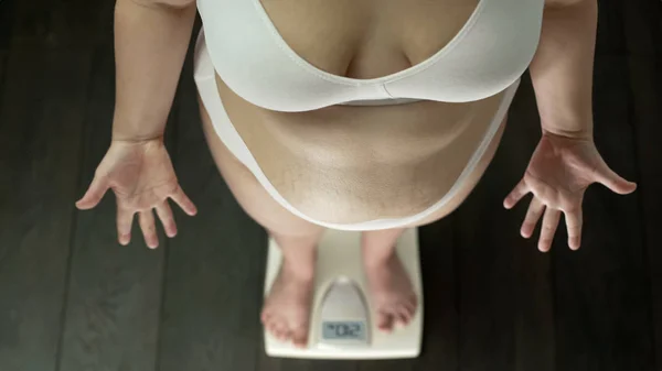 肥満女性の上に立ってスケール必死にジェスチャーの手 太った腹 トップ ビュー — ストック写真