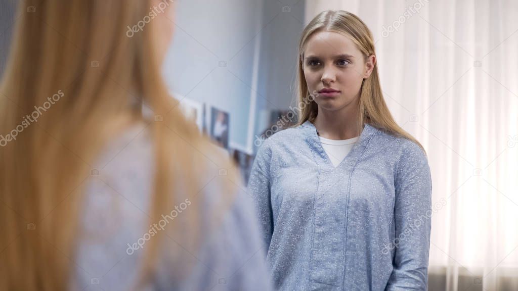 Teen looking at mirror reflection, upset about appearance, teenage insecurities