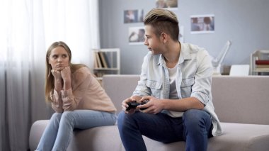 Girl angry at boyfriend for playing video games, quarrels because of addiction clipart