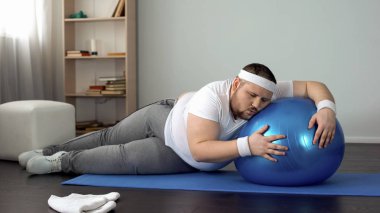 Fitness programı zayıflama fitness topu üzerinde yatan yorgun hiç motivasyonu olmayan obez adam
