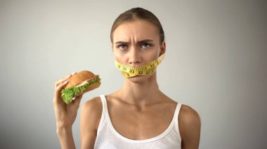 Bantlanmış ağzı ince kız kavgalar hamburger, günaha ile diyet