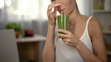 İğrenç yeşil smoothie, kapanış burun, kötü koku ve tat içme kadın