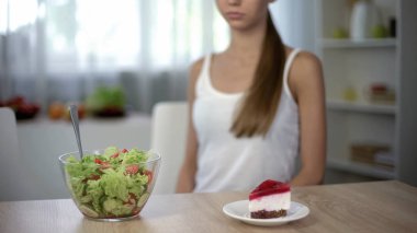 İnce kadın kek ve salata, sağlıklı beslenme arasında vs yüksek kalorili gıda seçimi