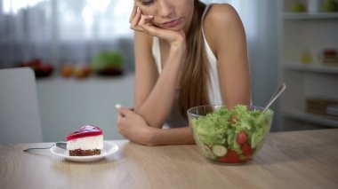 Seçme kek ve salata, sağlıklı beslenme vs yüksek kalorili gıda arasında ince erkek