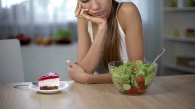 Slim female choosing between cake and salad, healthy diet vs high-calorie food clipart