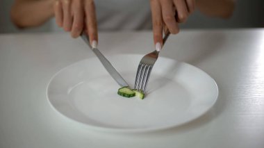 Girl slicing cucumber, obsessed with undereating, fear of overweight, anorexia clipart