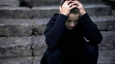 Eski kırık basamaklarında oturan korkmuş yalnız çocuk yankıları savaş, hayat yasta