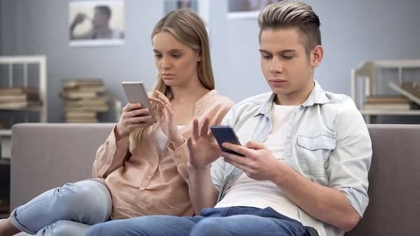 Pareja Enamorada Indiferentemente Sentada Sofá Mirando Sus Teléfonos Inteligentes — Foto de Stock