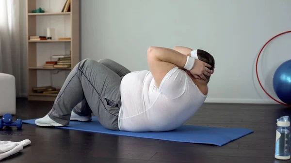 Fat belly man doing crunches, fitness program for weight loss, healthy lifestyle