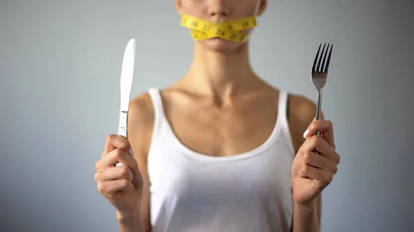 拒食症の女の子がフォークとナイフ 口を保持しているテープ 制限で閉鎖 — ストック写真