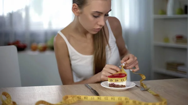 体重不足的女孩用胶带测量一块蛋糕 害怕体重增加 — 图库照片