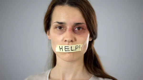 Woman with help sign on taped lips, helpless victim begging for support
