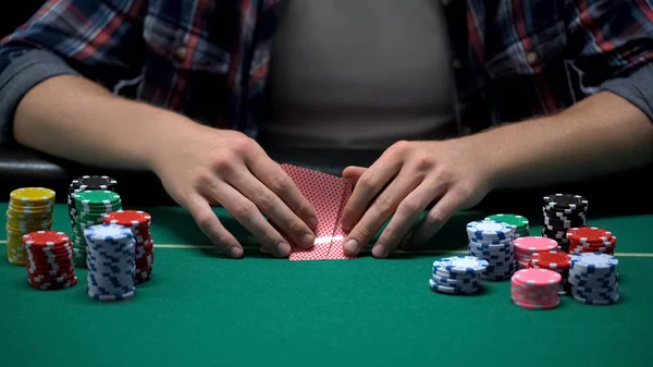 Male casino player checking his card combination in poker game tournament