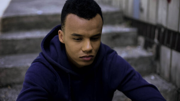 Hopeless afro-american teen sitting on steps in ghetto, concerned about future