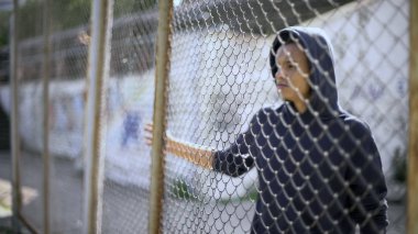 Migrant child separated from family, afro-american boy behind fence, detained clipart