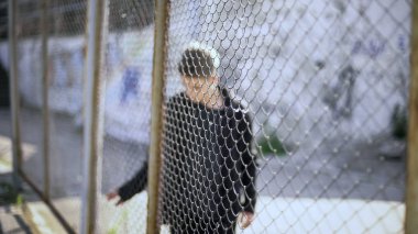 Teen boy behind fence confinement, boarding school restrictions, broken future clipart