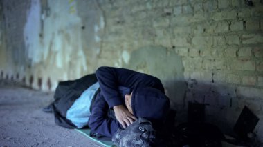 Sokak, kayıtsız egoist toplum üzerinde yoksulluk uyuyan evsiz bir genç adam