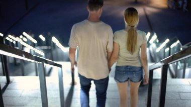 El ele tutuşarak, alt katta gece şehirde, beraberlik yürüyen genç çift