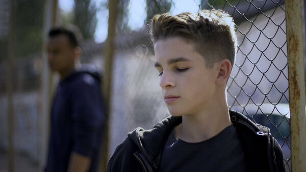 Teenage boys leaning on metal fence, juvenile detention center, orphanage