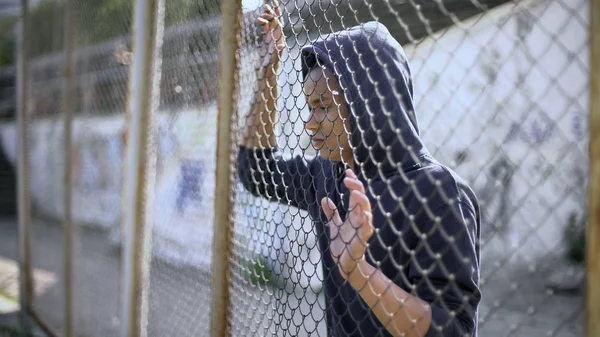 移民少年在栅栏后面梦想光明的未来和安全 — 图库照片
