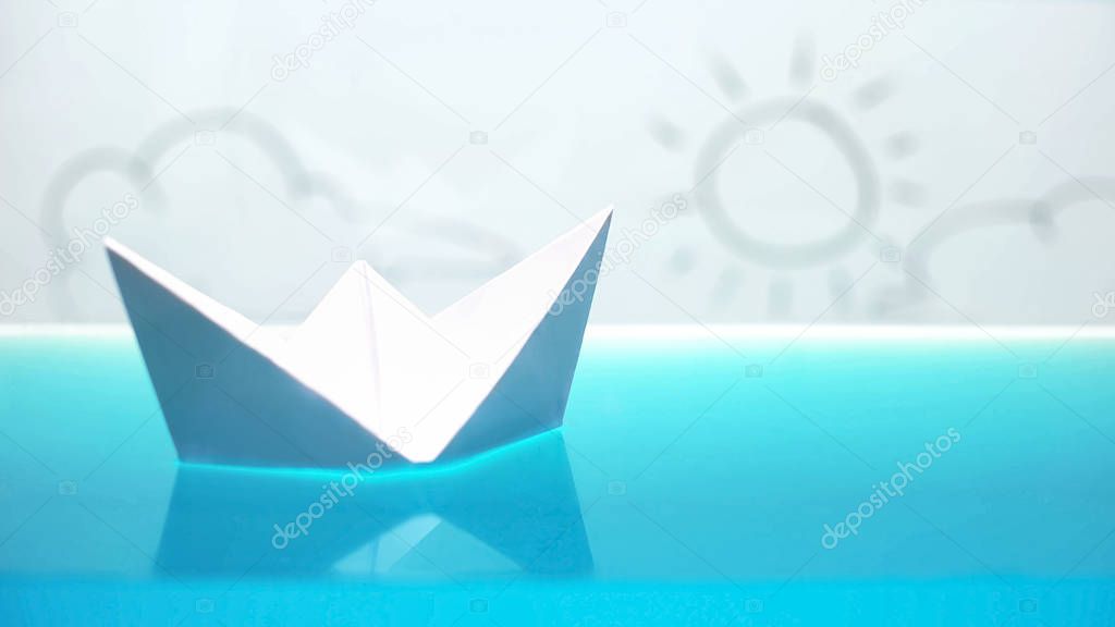 Paper boat floating in bath, happy sunny future on horizon, dreams, macro shot