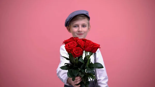 Liten Kjekk Gutt Som Viser Fram Røde Roser Til Kamera – stockfoto