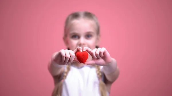 Маленькая Улыбающаяся Девочка Косичками Показывает Игрушечное Сердце Фотоаппарате Крупным Планом — стоковое фото