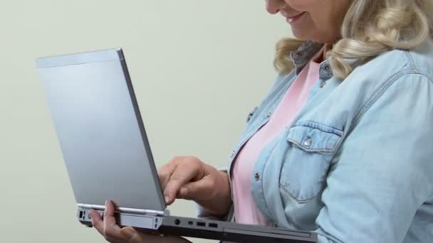 Pensionista Femenina Escribiendo Ordenador Portátil Cámara Sonriente Banca Línea Internet — Vídeos de Stock