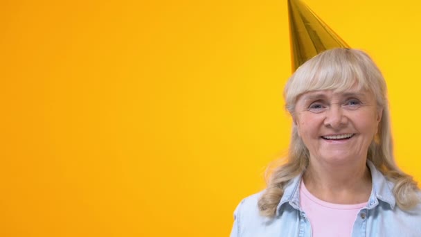 Alegre Abuela Sombrero Fiesta Mostrando Globos Naranja Sobre Fondo Amarillo — Vídeos de Stock