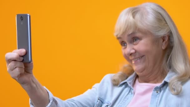 年配の女性のスマート フォンで Selfie を取って楽しんで愚かな顔を作る — ストック動画