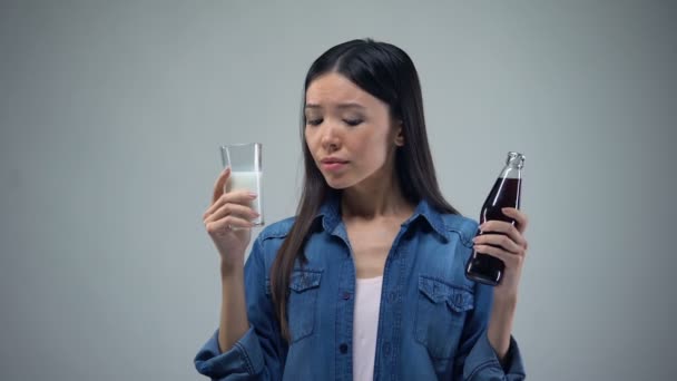 不健康な炭酸飲料と役に立つ健康的な牛乳を選んだとする女 — ストック動画