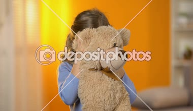 Oynak sevimli kız peluş oyuncak gizleme ve kameraya gülümseyen iskambil