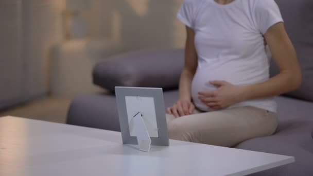 不幸な妊娠未亡人のフレームで写真を見て孤独に苦しんでいます — ストック動画